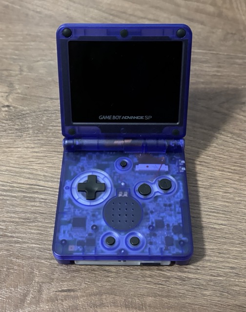 A Nintendo Game Boy Advance SP, laying on the table, opened up.