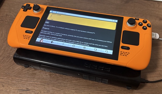 A black Nintendo Wii U, with a Valve Steam Deck on top of it. The Steam Deck shows the Wii U Browser showing the homepage of gloriaaaa.eu.